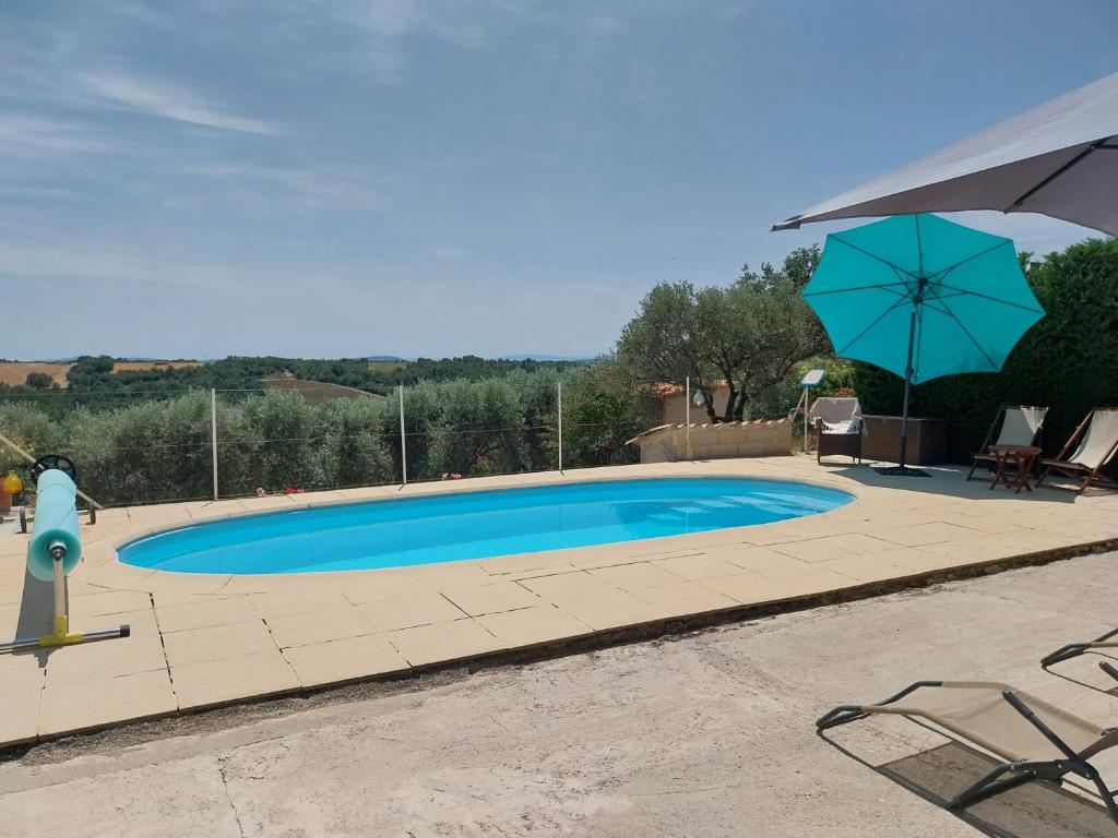 une piscine avec un parasol, une table et des chaises dans l'établissement Gîtes Lou Limbert Plateau de Valensole, à Valensole