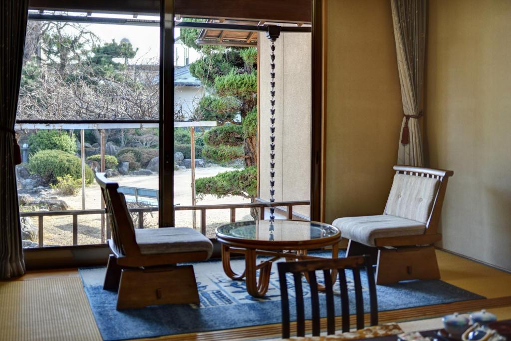 un salon avec une table et des chaises et une fenêtre dans l'établissement Rakusuien, à Kōfu