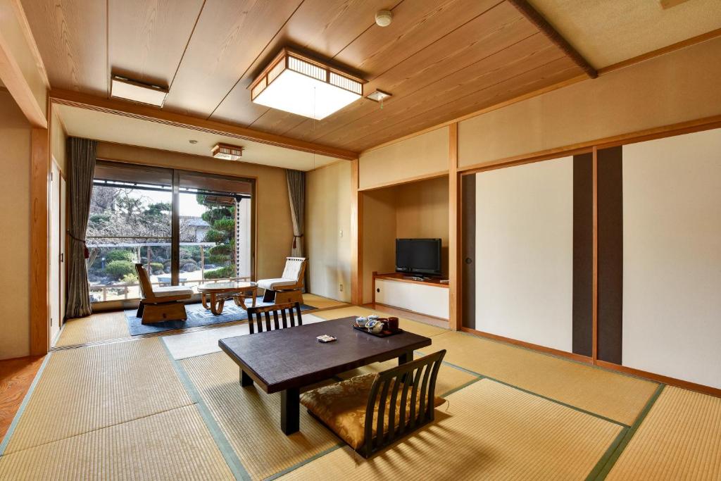 un salon avec une table et une télévision dans l'établissement Rakusuien, à Kōfu