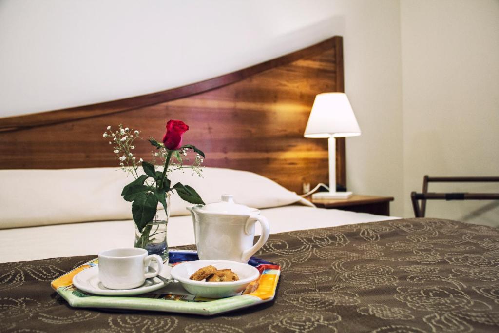 une table avec un plateau de nourriture et un vase avec une rose dans l'établissement Hotel Sirenetta, à Isola delle Femmine