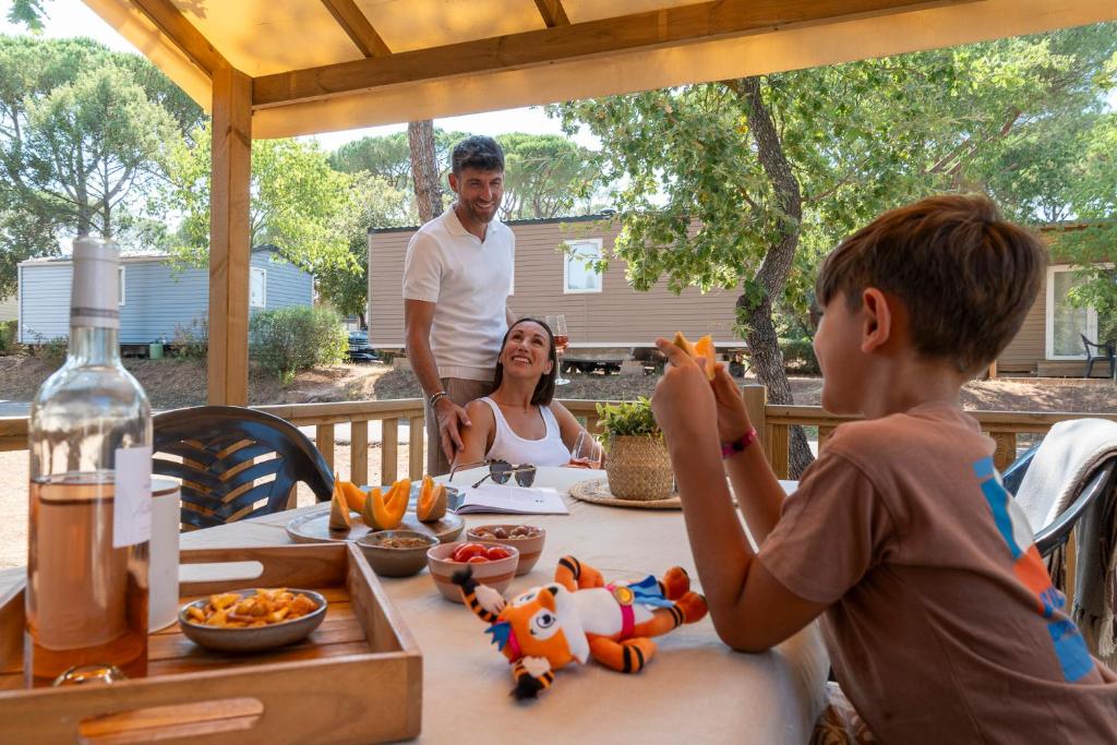 un homme et une femme assis à une table avec un enfant dans l'établissement Camping les Cigales, au Muy 31 autres photos