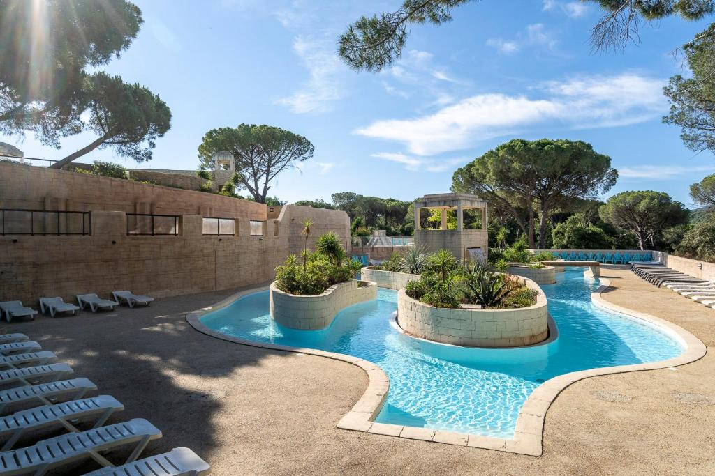 une piscine avec des chaises longues devant un immeuble dans l'établissement Camping les Cigales, au Muy