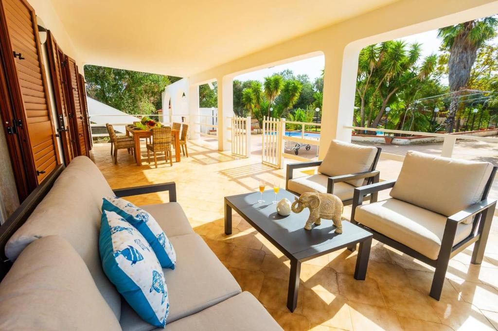 un salon avec un canapé, des chaises et une table dans l'établissement Villa Olivier by Villa Plus, à Carovigno