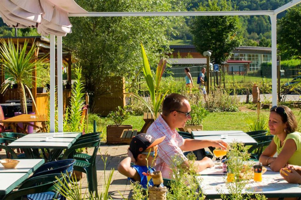 un homme et une femme assis à une table dans un jardin dans l'établissement Glamping Ornans, à Ornans