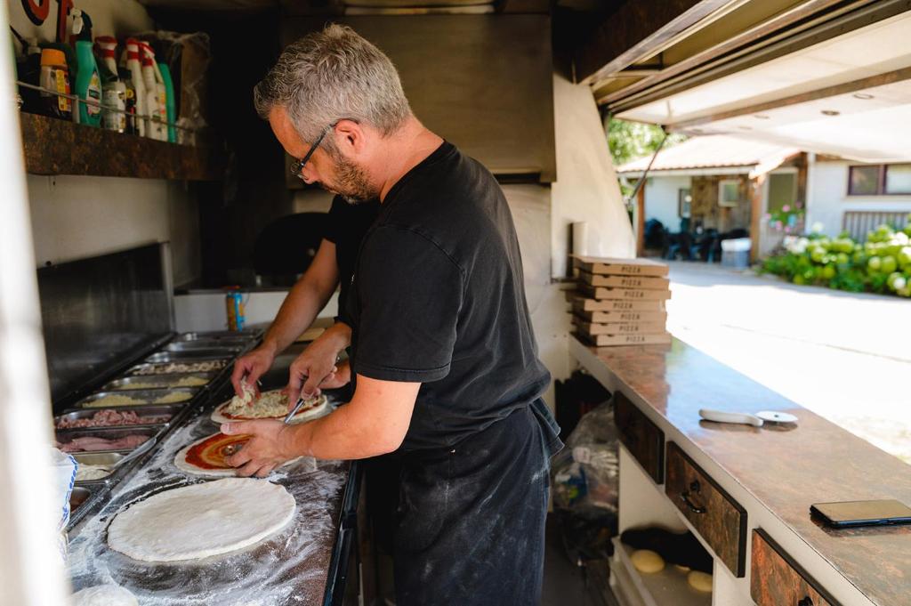 un homme préparant de la nourriture sur un comptoir dans une cuisine dans l'établissement Glamping the Vosges, à Corcieux