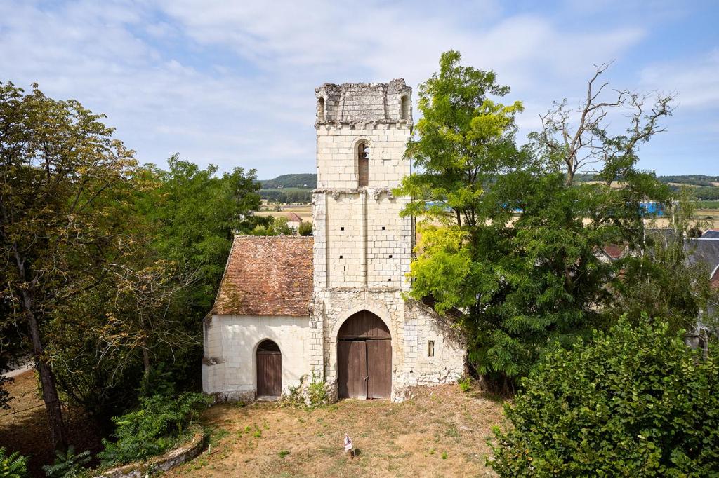 un ancien bâtiment en pierre avec une tour sur un champ dans l'établissement Glamping Loire Valley, à Ingrandes