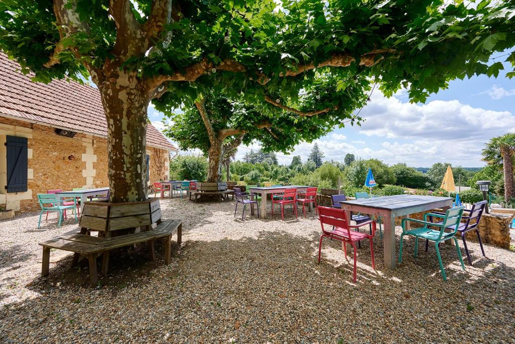 un groupe de tables et de chaises sous un arbre dans l'établissement Glamping Dordogne, à Douville