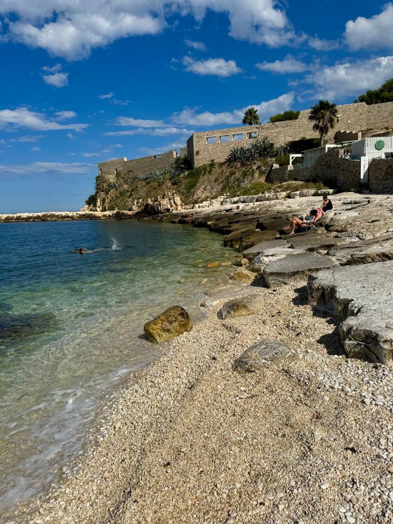 une plage rocheuse avec des gens qui nagent dans l'eau dans l'établissement Samarè Rooms & Apartments, à Bisceglie