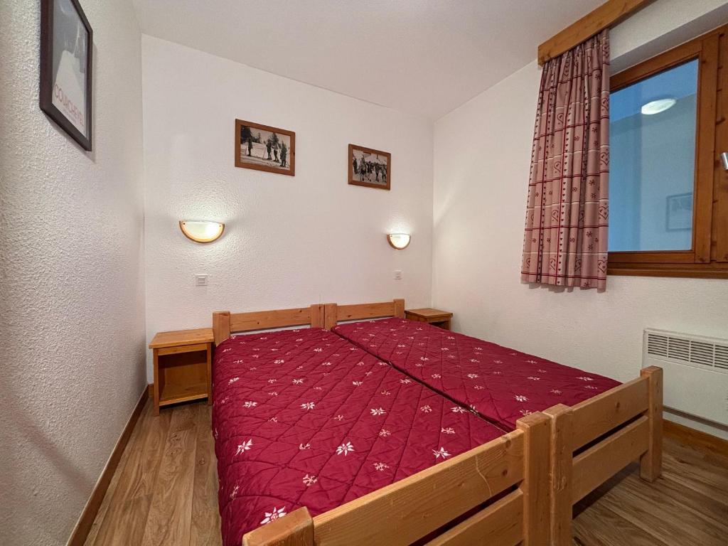 une chambre avec un lit avec une couette rouge dans l'établissement Résidence Saboia Clés Blanches, à La Tania