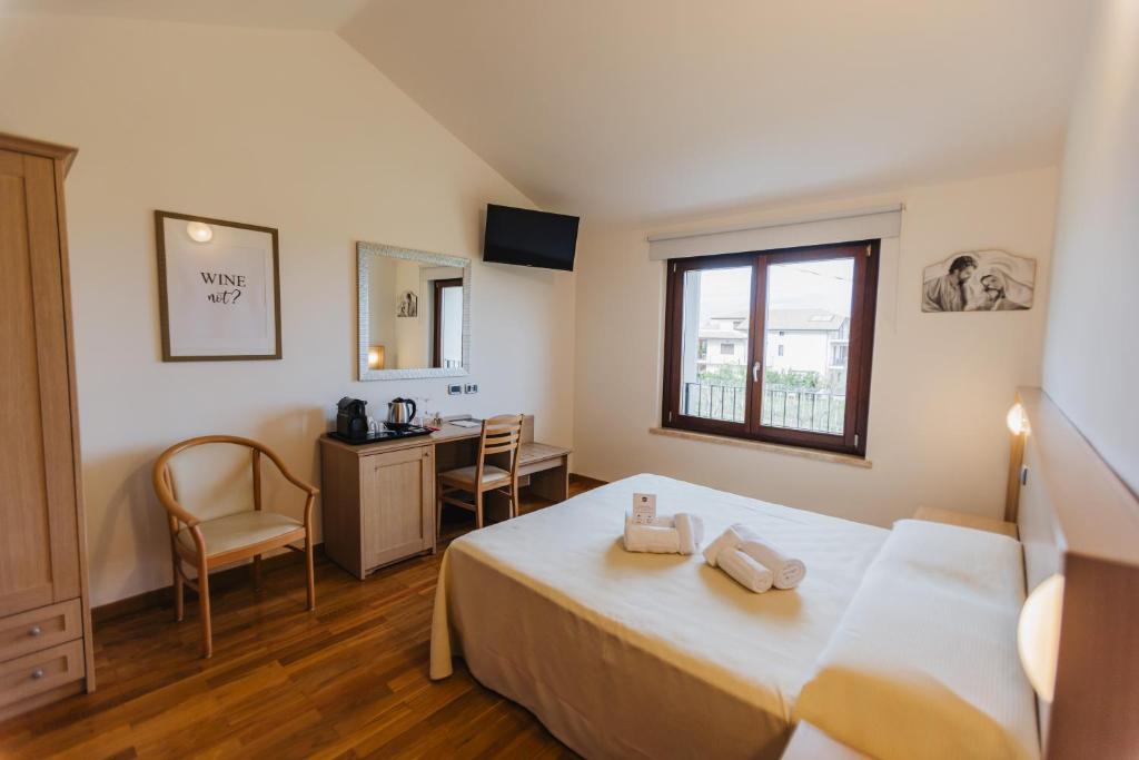 une chambre avec un lit, un bureau et une fenêtre dans l'établissement Magnificat Hotel&Resort, à Canosa Sannita