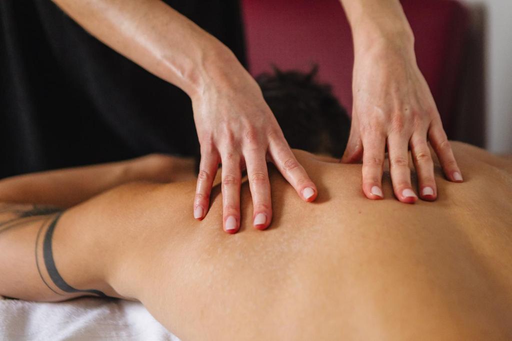 une femme recevant un massage du dos par un thérapeute dans l'établissement Magnificat Hotel&Resort, à Canosa Sannita