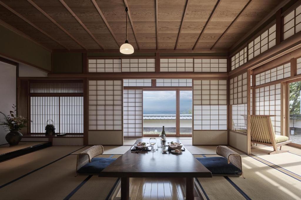une pièce avec une table, des chaises et des fenêtres dans l'établissement THE HIRAMATSU HOTELS & RESORTS ATAMI, à Atami
