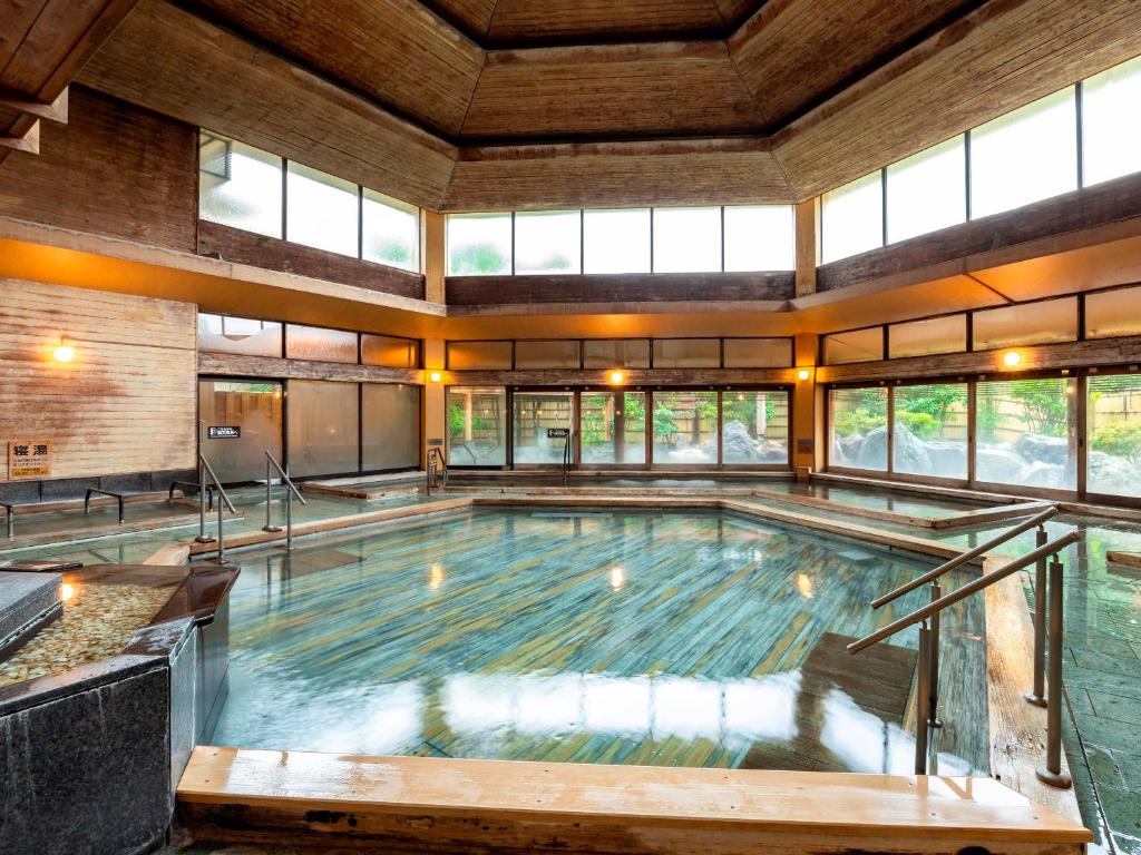 - une grande piscine dans une grande pièce dotée de fenêtres dans l'établissement Hotel Sunvalley Izunagaoka Main Building, à Izunokuni