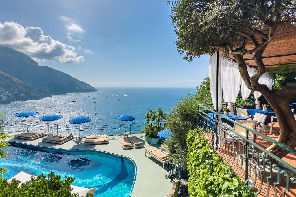 une piscine avec chaises et parasols au bord de l'océan dans l'établissement Hotel Le Agavi, à Positano