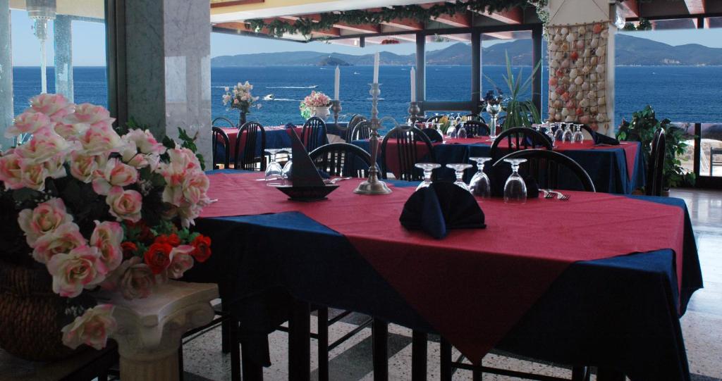 une table avec une nappe rouge et des fleurs dessus dans l'établissement Hotel Esperia, à Piombino