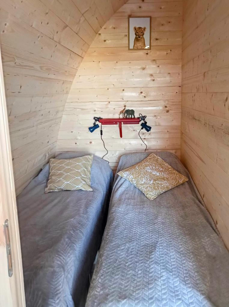 une chambre avec deux lits dans une cabane en bois dans l'établissement Safaripod Les Pourettes, à Feusines