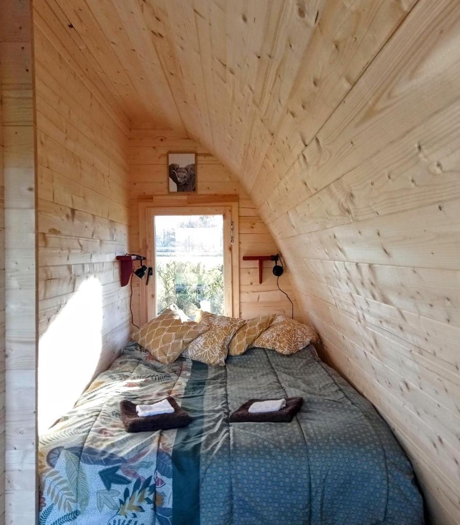 - un lit dans une petite maison avec fenêtre dans l'établissement Safaripod Les Pourettes, à Feusines