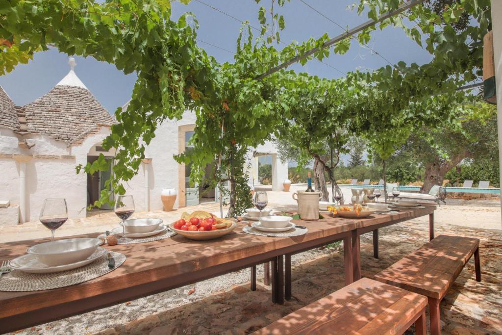 une table en bois avec des fruits sur elle sous un arbre dans l'établissement TD Marlù Luxury Trulli Experience with Stunning Pool, à Castellana Grotte