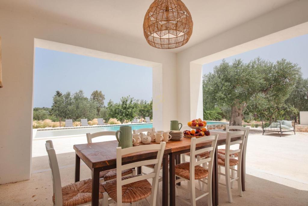 une salle à manger avec une table et des chaises et une grande fenêtre dans l'établissement TD Marlù Luxury Trulli Experience with Stunning Pool, à Castellana Grotte