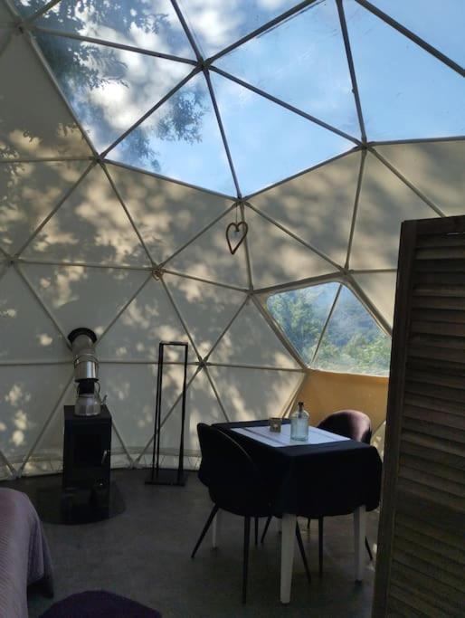 une chambre avec une table et des chaises dans un dôme en verre dans l'établissement Dôme de l'Arriou, à Ourde