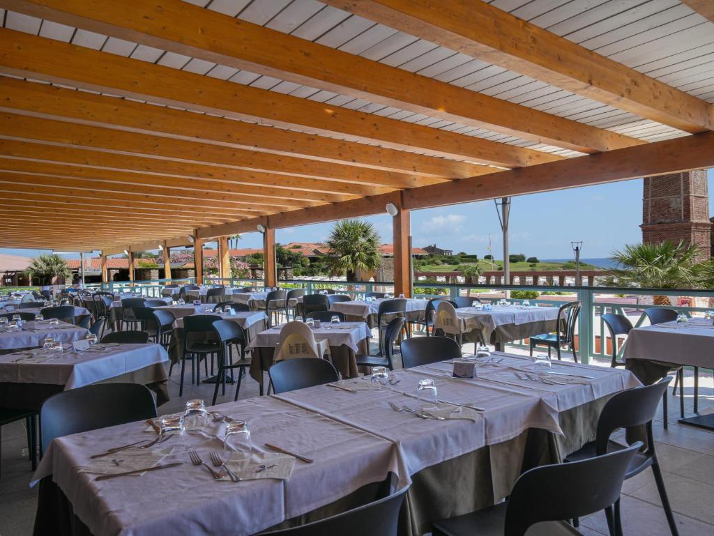 une rangée de tables et de chaises dans un restaurant dans l'établissement Le Tonnare di Stintino - Beach Resort, à Stintino