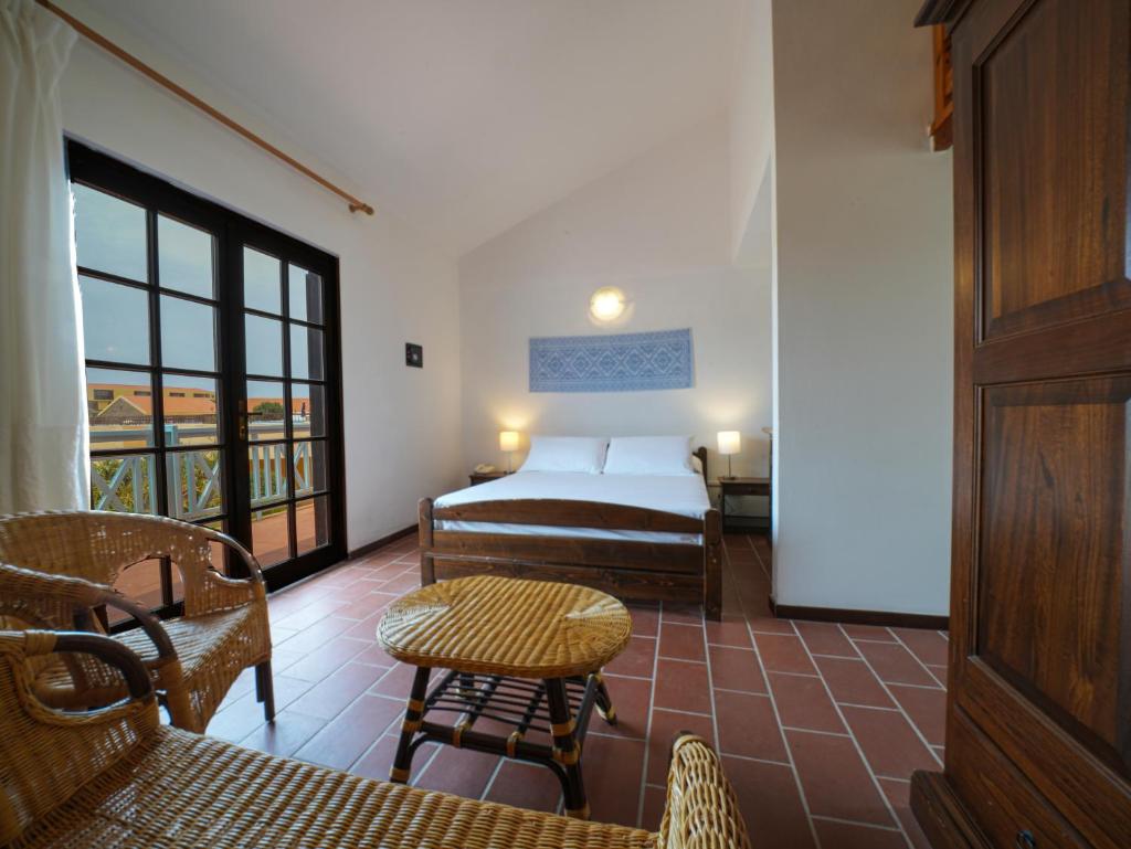 une chambre avec un lit, une table et des chaises dans l'établissement Le Tonnare di Stintino - Beach Resort, à Stintino