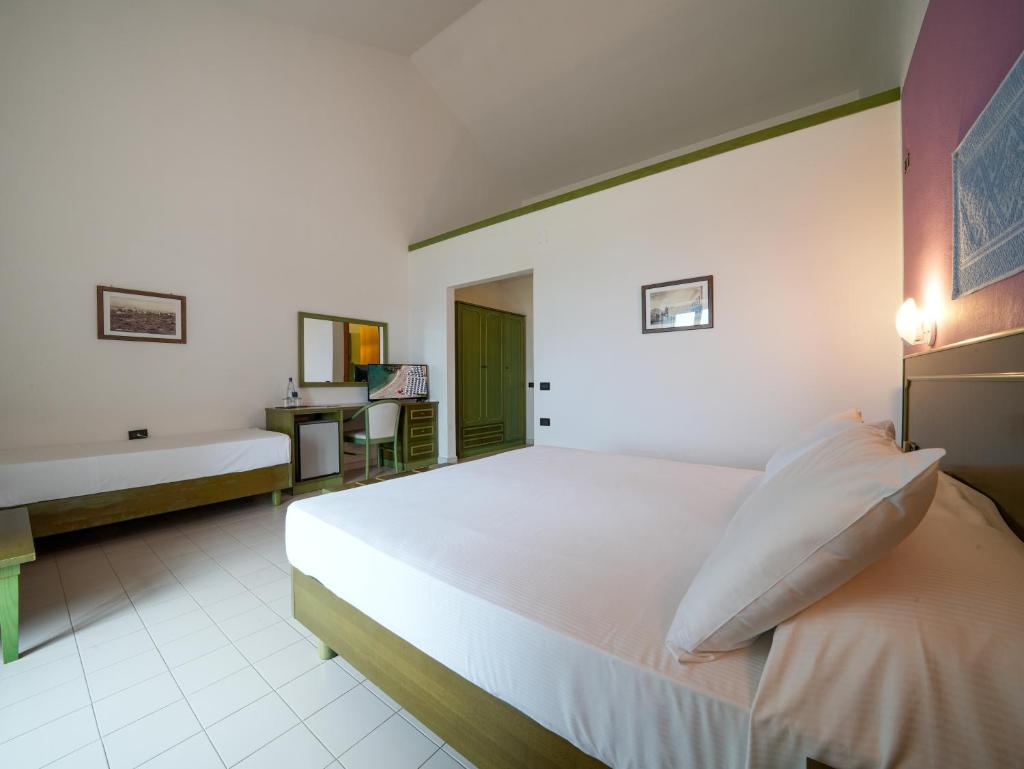 une chambre avec un grand lit blanc et un bureau dans l'établissement Le Tonnare di Stintino - Beach Resort, à Stintino 25 autres photos