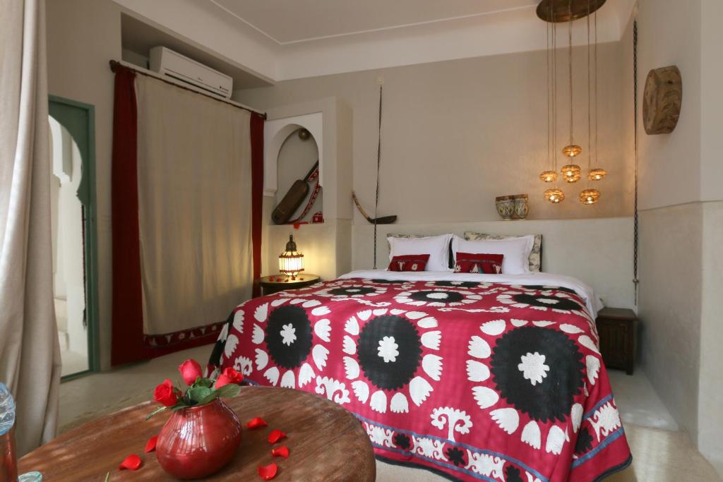 - une chambre avec un lit rouge et blanc et une table dans l'établissement Riad Dar Ayur, à Marrakech