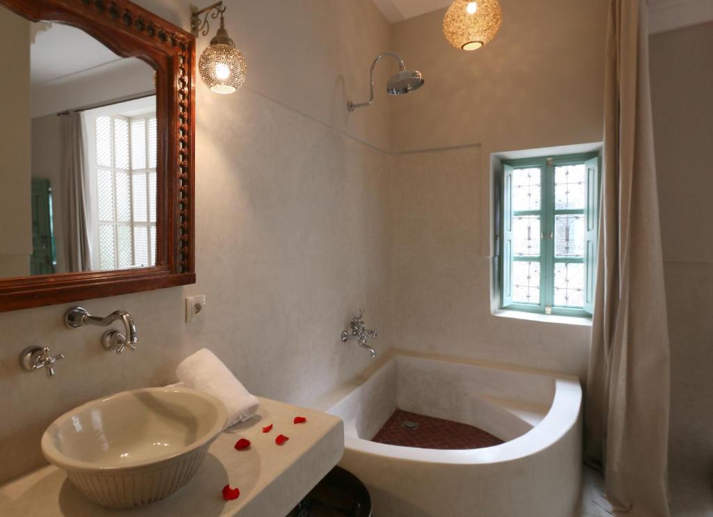 une salle de bain avec une baignoire, un lavabo et un miroir dans l'établissement Riad Dar Ayur, à Marrakech