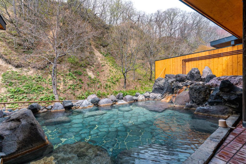 une grande piscine d'eau avec des rochers devant un bâtiment dans l'établissement Yuyado DAIICHI, à Naka-shibetsu