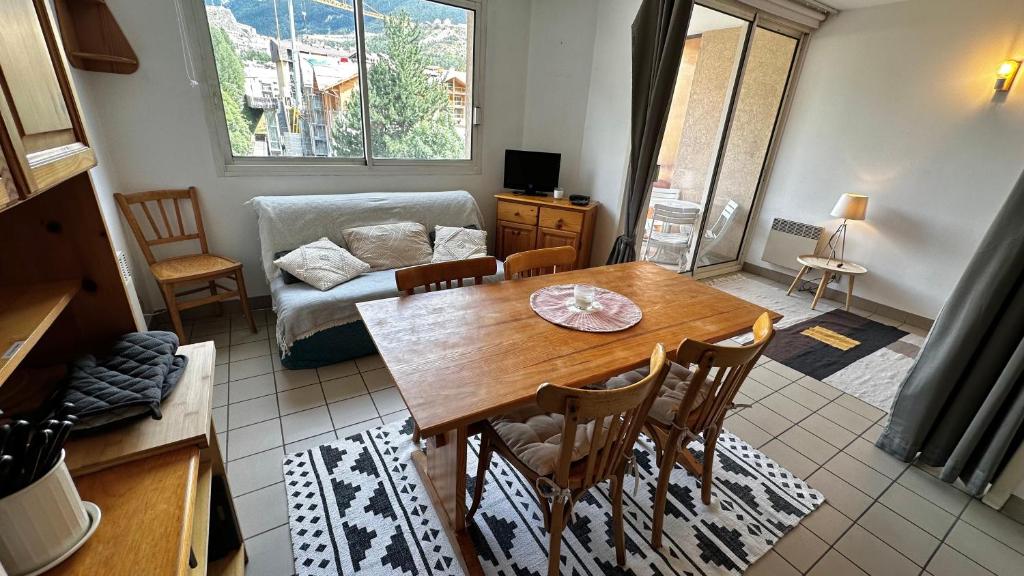 un salon avec une table, des chaises et un canapé dans l'établissement Appartement Centre Ville pied de piste Briançon, à Briançon