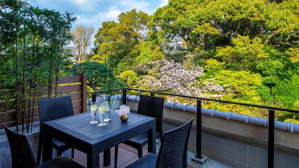 une table et des chaises sur un balcon arboré dans l'établissement Yanagawa Hakuryuso, à Yanagawa