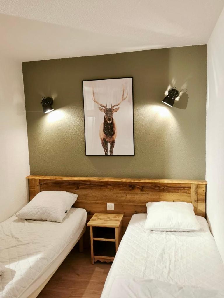Deux lits dans une chambre avec une photo d'un cerf sur le mur dans l'établissement Pierre et Vacances Les Bergers au Pied des pistes & Piscine -Sauna & Balcon Sud, à L'Alpe-d'Huez