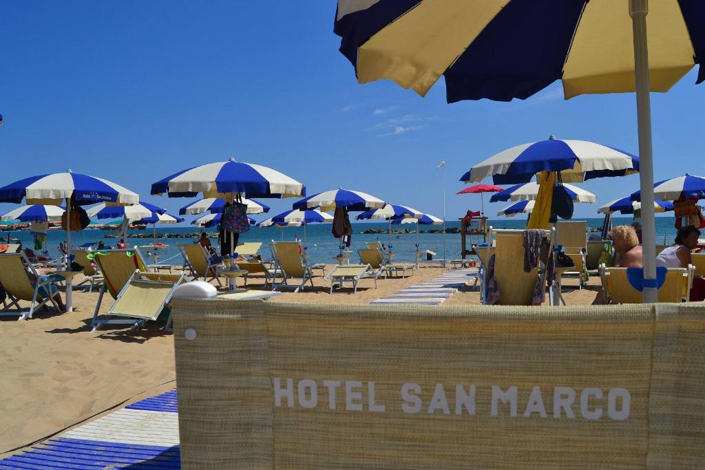 une plage avec des parasols et des gens assis sur le sable dans l'établissement Hotel San Marco, à Francavilla al Mare