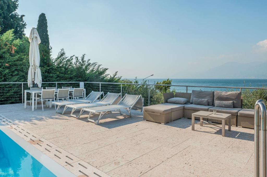 d'une terrasse avec un canapé et des chaises à côté de la piscine. dans l'établissement VillasGarda - Villa Lorena Carbona, à Torri del Benaco