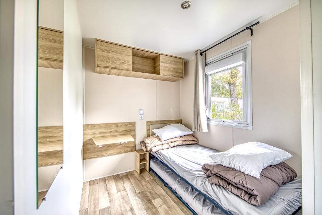 une petite chambre avec un lit et une fenêtre dans l'établissement Mobil home Amira 42m2, à Lège-Cap-Ferret
