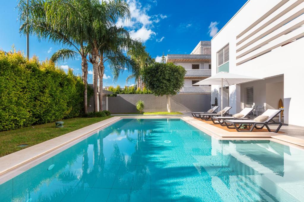 une piscine avec des chaises et une maison dans l'établissement Villa Acquadimare - Pool Terrace Jacuzzi, à Lecce