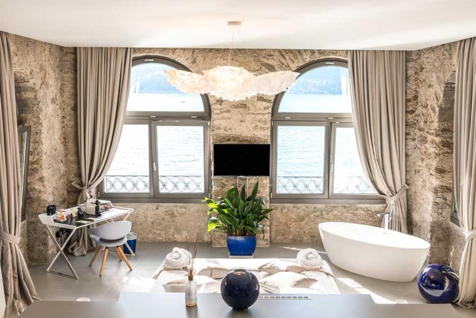 une salle de bain avec une baignoire, une table et des fenêtres dans l'établissement Relais Villa Porta, à Luino