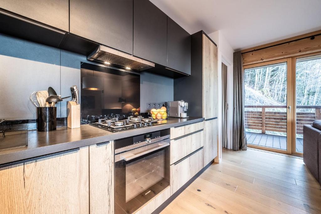 une cuisine avec des armoires noires et un four à plaques de cuisson dans l'établissement Maira Les Carroz - by EMERALD STAY, à Arâches-la-Frasse