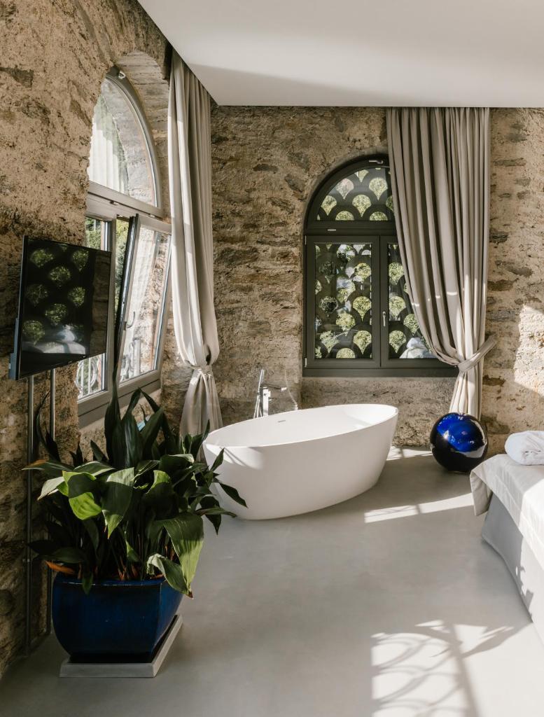 La salle de bains est pourvue d'une grande baignoire blanche et de fenêtres. dans l'établissement Relais Villa Porta, à Luino