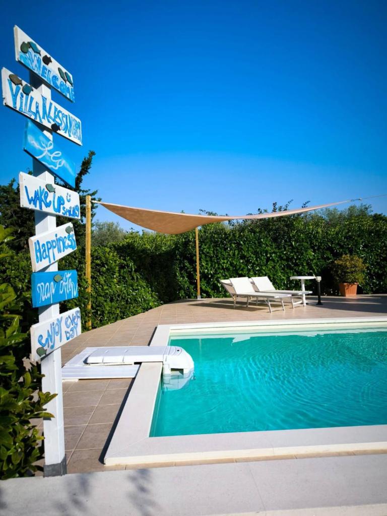 - une piscine avec un panneau en face d'une maison dans l'établissement Villa Alessandra, à Monopoli
