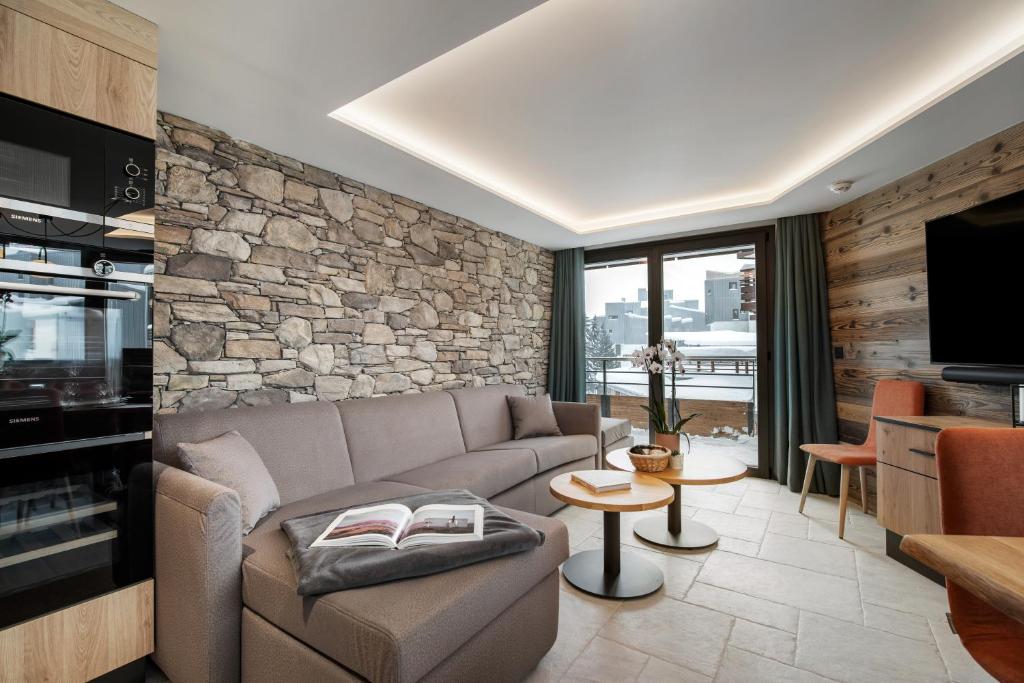 un salon avec un canapé et un mur en pierre dans l'établissement Chalet Hôtel Quartz, à Tignes
