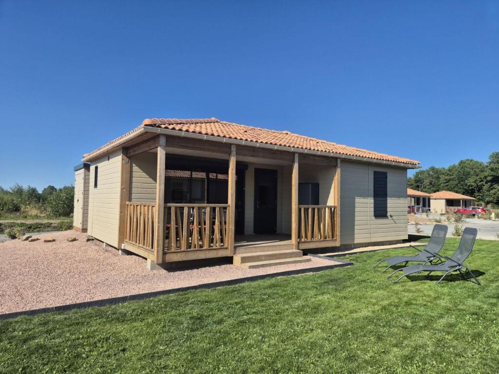 une petite maison avec une terrasse et deux chaises dans l'établissement Chalet dans domaine avec piscine, à Marzan