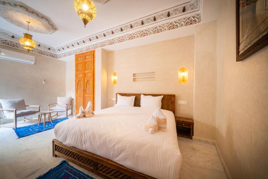 une chambre avec un grand lit avec des draps blancs dans l'établissement Riad Nadalinn, à Marrakech