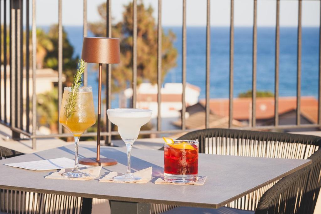 - une table avec deux boissons et une lampe dans l'établissement Hotel Netum Mare, à Noto Marina