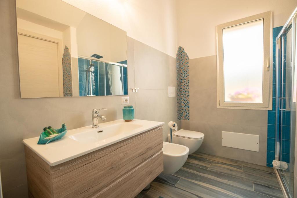 une salle de bain avec un lavabo et des toilettes et une fenêtre dans l'établissement Villa S'Ena e su Juncu, à Loculi