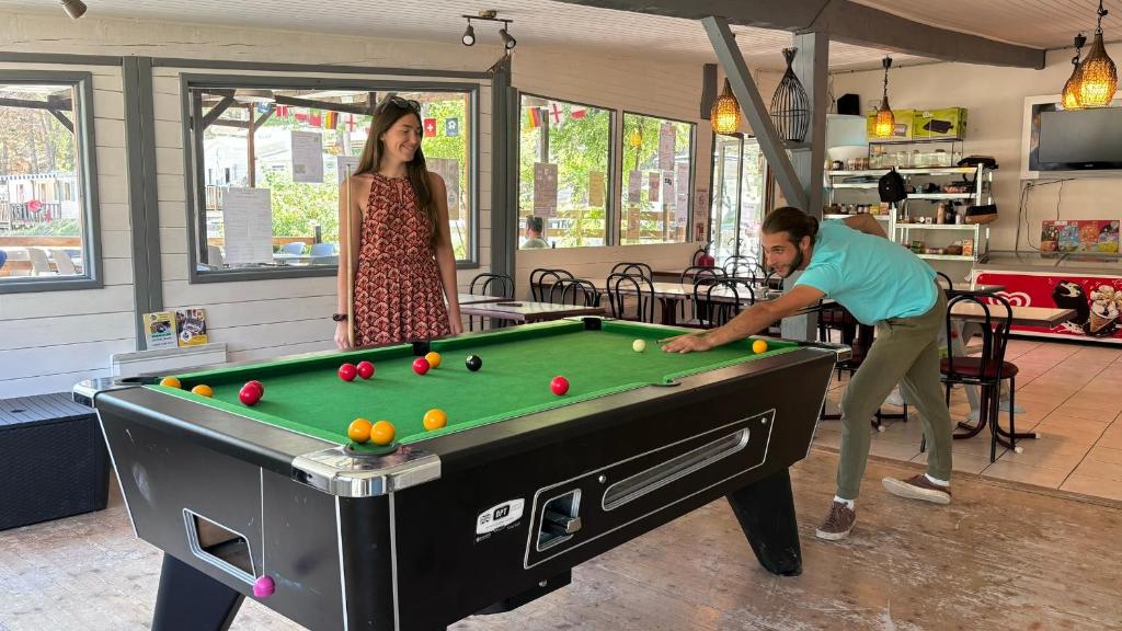 un homme et une femme jouant au billard dans l'établissement Camping La Pinatelle, à Saint-Auban