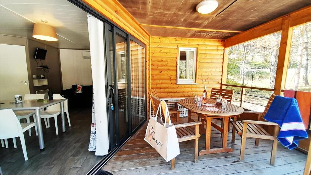 une salle à manger avec une table et des chaises sur un porche dans l'établissement Camping La Pinatelle, à Saint-Auban