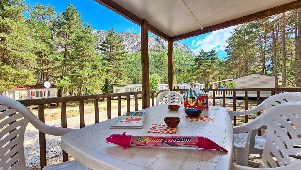 - une table et des chaises sur une terrasse couverte offrant une vue sur les montagnes dans l'établissement Camping La Pinatelle, à Saint-Auban