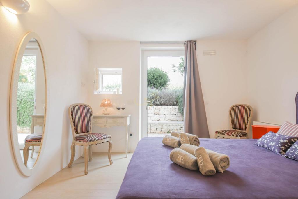 une chambre avec un lit et deux chaises et un miroir dans l'établissement TD Il Vecchio Fienile Outdoor Kitchen with Pool View, à Polignano a Mare